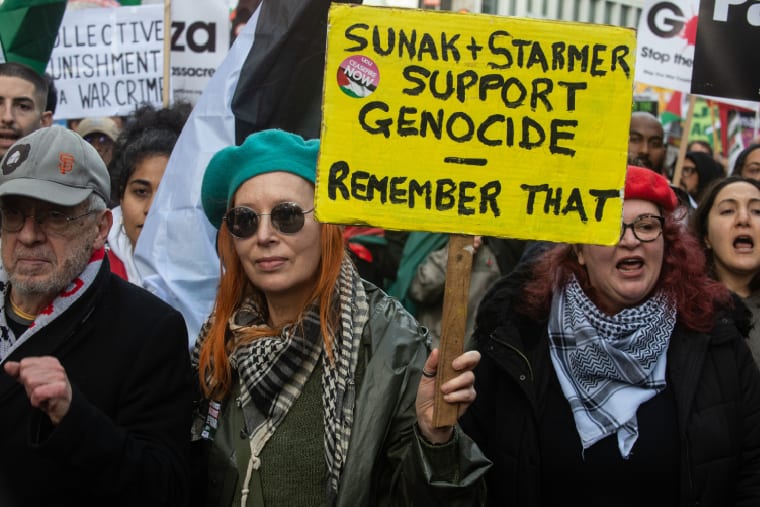 Le manifestant tient une pancarte sur une manifestation en Palestine qui indique que Tory Sunak et Starmer du parti travailliste soutiennent le génocide, rappelez-vous que 